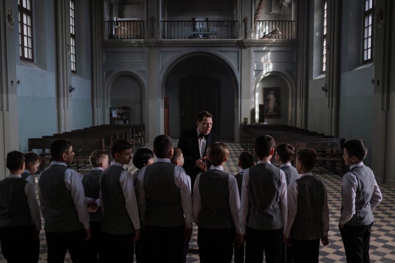 about-03 Boys choir rehearsing under conductor in an elegant cathedral setting.